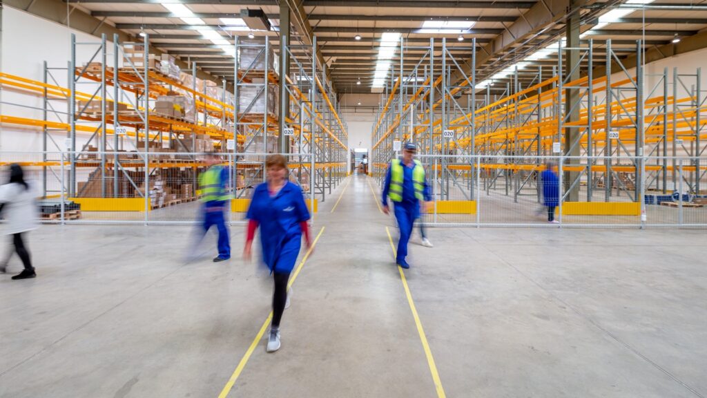 Workers in a warehouse walking around.