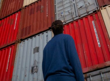 A man gazing upwards at stacked storage containers.