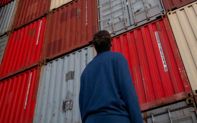 A man gazing upwards at stacked storage containers.