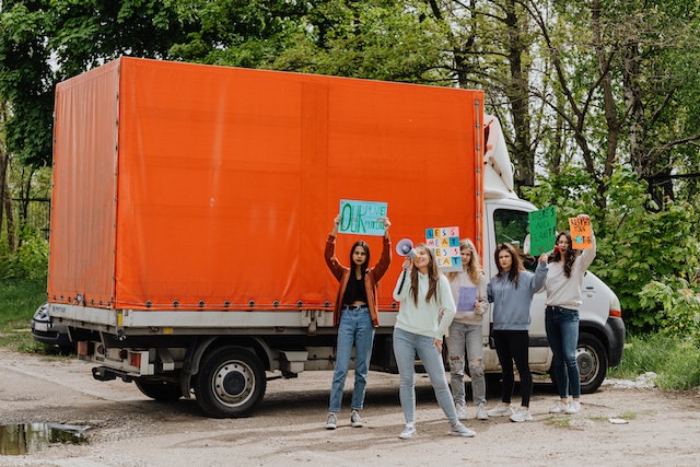 Group of women standing next to an orange truck