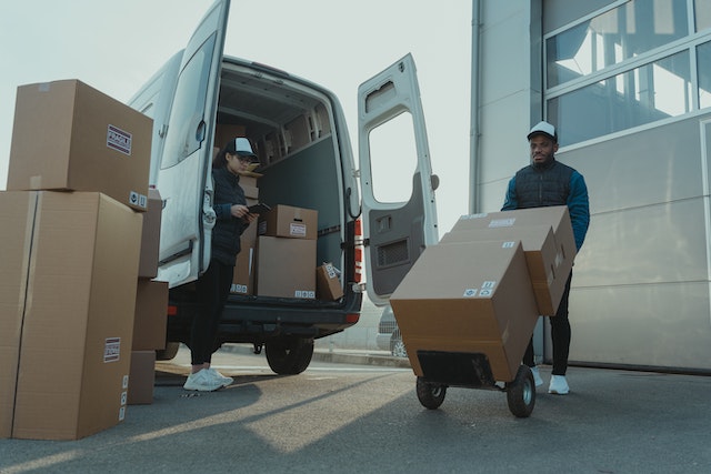 Man and a woman unloading a van full of boxes